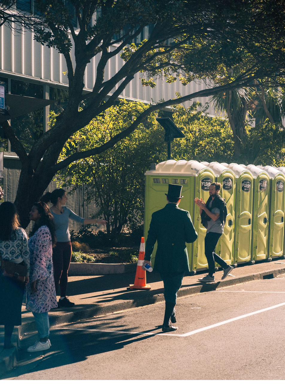 Row of standard portable toilets set up along a public sidewalk